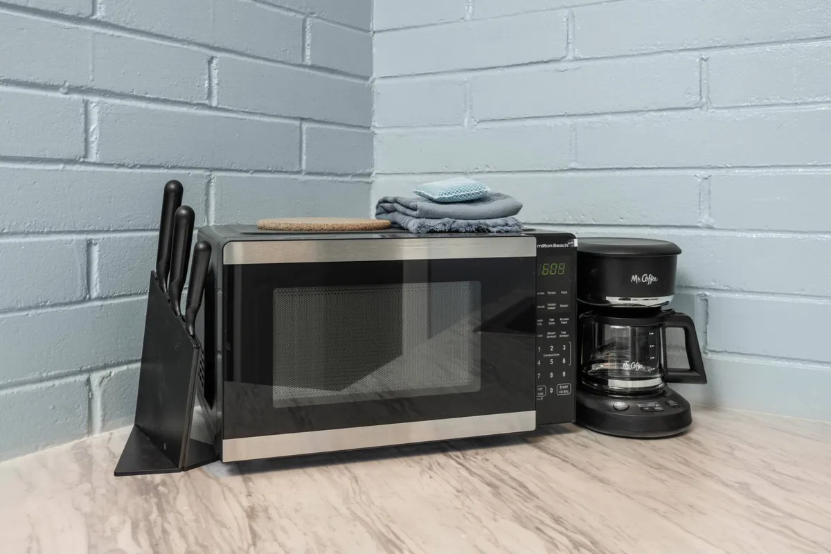 This image focuses on key small appliances including a microwave and coffee maker, as well as a knife block, all arranged on a tidy counter. The mood is practical and welcoming, suggesting a space tailored for simple meal routines and quick refreshments.
