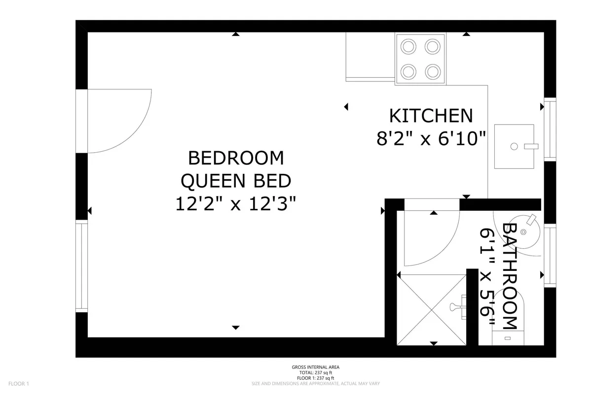 A view into a cozy cottage interior, showing a queen bed, a kitchen area, and bathroom. The space feels intimate and practical, emphasizing comfort and convenience for both guests and their pets after beach adventures.